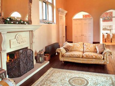 A living room with a sofa a fireplace and a rug at The Hall in Belford