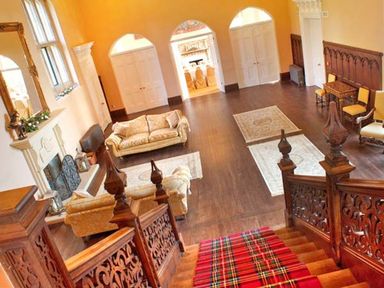 A sitting room with a fireplace sofas and rugs viewed from a wooden staircase at The Hall in Belford