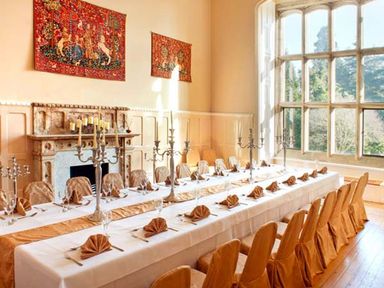 A dining room with a long table set with napkins glasses cutlery and candelabras near a large window at The Hall in Belford
