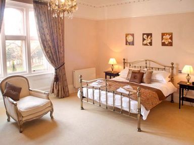 A bedroom with a double bed armchair two bedside tables with lamps and three framed pictures on the wall at The Hall in Belford