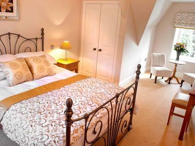 A bedroom with a metal bed frame and bedding a bedside table with a lamp a wardrobe two chairs and a small round table with a flower vase at The Hall in Belford