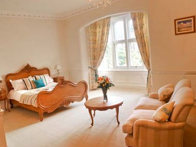 A bedroom with a wooden bed sofa and a round table with flowers at The Hall in Belford