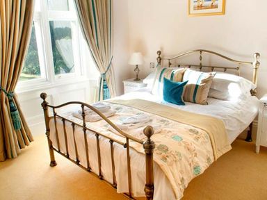 A bedroom with a metal framed bed beside windows with curtains at The Hall in Belford