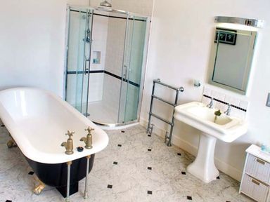 A bathroom with a clawfoot bathtub a glass shower cubicle a pedestal sink with mirror and a towel rack at The Hall in Belford