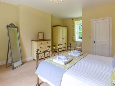 A bedroom with a metal bed frame dresser wardrobe standing mirror and window with curtains at The Hall in Belford