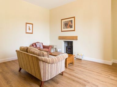 A sitting room with a sofa armchair wooden coffee table and framed pictures on the wall at The Coach House in Belford