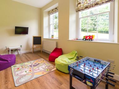 A playroom with bean bags a foosball table a small table with chairs a chalkboard and toy vehicles at The Coach House in Belford