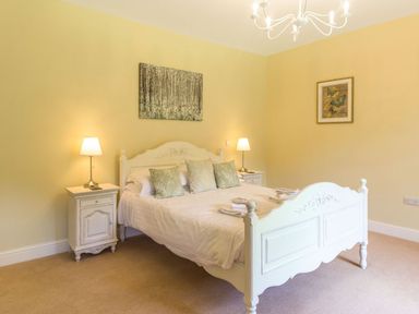 A bedroom with a white bed and bedside tables with lamps and wall art at The Coach House in Belford