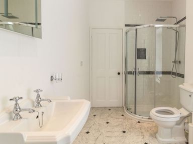 A bathroom with a double sink, glass shower enclosure, and toilet at The Coach House in Belford
