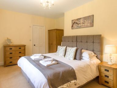 A bedroom with a double bed wooden wardrobe chest of drawers bedside table at The Coach House in Belford