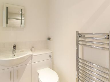 A bathroom with a sink toilet mirror and chrome heated towel rail at The Coach House in Belford