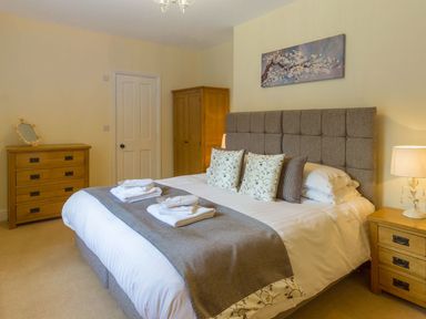 A bedroom with a large bed pillows bedside tables lamps and wooden furniture at The Coach House in Belford