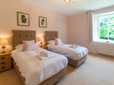 A bedroom with two single beds lamps and a window at The Coach House in Belford