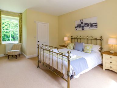 A bedroom with a metal bed frame bedside tables lamps and a window with curtains at The Coach House in Belford