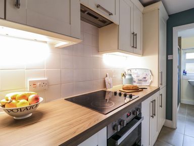 A kitchen countertop with fruit bowl stove bread kettle and cabinets at Compass Cottage in Aldeburgh