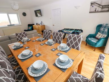 A dining room with a table set for meals at 15 Lawnswood in Saundersfoot