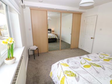 A bedroom with a bed and mirrored wardrobe at 15 Lawnswood Saundersfoot