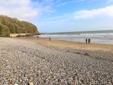 A beach with people walking near the water at 15 Lawnswood Saundersfoot