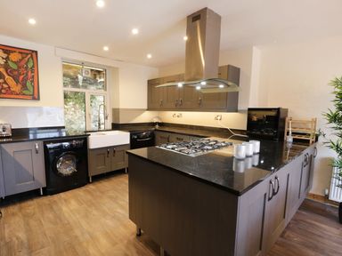 A kitchen with an island with a gas stove and overhead extractor fan at Old Post Office in Blaenau Ffestiniog