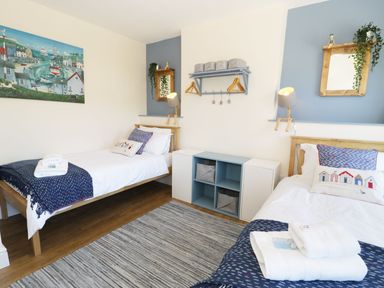 A bedroom with two single beds wooden mirrors and a shelf with hangers at Old Post Office in Blaenau Ffestiniog
