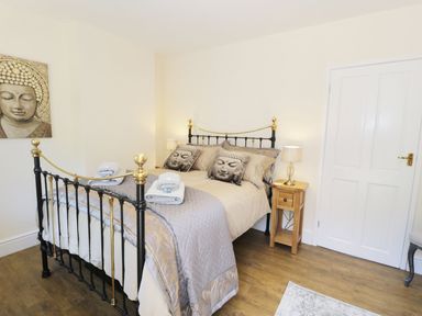A bedroom with a metal bed frame black and gold bedside tables lamps and buddha-themed pillows at Old Post Office in Blaenau Ffestiniog