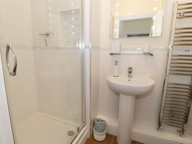 A bathroom with a shower enclosure a pedestal sink a towel rack and toiletries at Old Post Office in Blaenau Ffestiniog