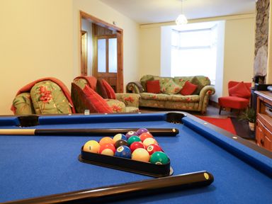 A room with a blue pool table and floral sofas with red cushions at Old Post Office in Blaenau Ffestiniog