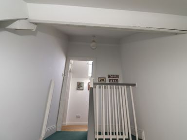 A hallway with white walls green carpet and a white stair railing at Ocean View in Alnmouth