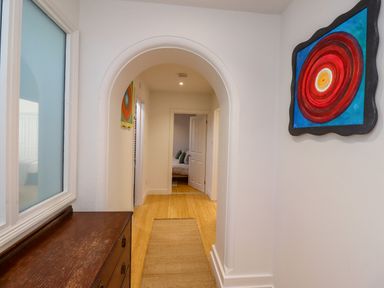 A hallway with wooden floor a console table and a colorful painting at Ocean View in Alnmouth