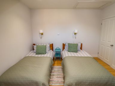A bedroom with two single beds a small blue bedside table and wall lamps Ocean View Alnmouth