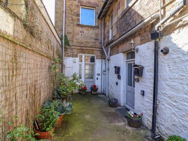 A small outdoor courtyard with potted plants and two doors with mailboxes at Ocean View in Alnmouth
