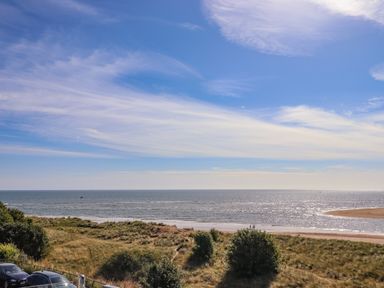 A beach with sand dunes and grassy vegetation by the sea under a blue sky at Ocean View in Alnmouth