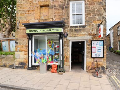 Front of Alnmouth Village Store with various nets and toys in a metal bin and an open door at Ocean View in Alnmouth