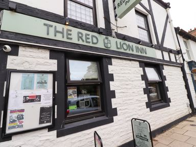 Exterior of The Red Lion Inn with black and white stone walls and promotional posters on the windows and walls at Ocean View in Alnmouth