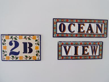 Decorative ceramic tiles with the text 2B and Ocean View on a white wall at Ocean View in Alnmouth