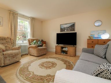 A living room with armchairs a sofa a round rug a television and a wooden cabinet at Archie's in Minehead