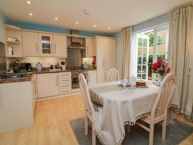A kitchen with a dining table and flowers by glass doors at Archie's in Minehead