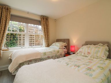 A bedroom with two single beds and a window with curtains at Archie's in Minehead