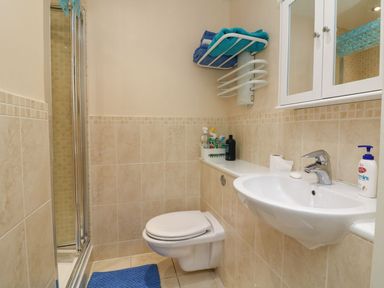 A bathroom with a wall-mounted toilet a sink a shower enclosure and a towel rack with blue towels at Archie's Minehead