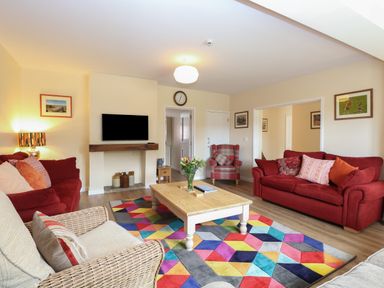 A living room with red sofas a colorful geometric rug and a wooden coffee table at Beach House in Winterton-On-Sea