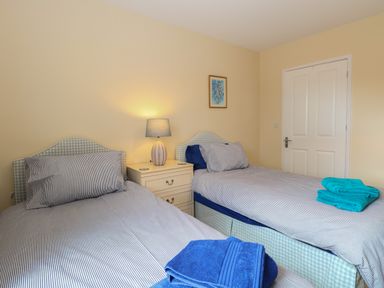 A bedroom with two single beds with striped bedding a bedside table with a lamp and folded towels at Beach House Winterton-On-Sea