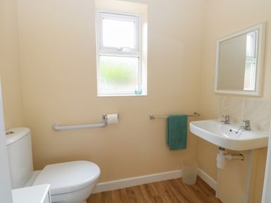 A bathroom with a toilet sink mirror window and a towel at Beach House in Winterton-On-Sea