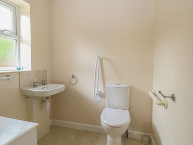 A bathroom with a toilet and a wall-mounted sink next to a window at Beach House in Winterton-On-Sea