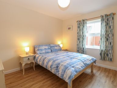 A bedroom with a double bed with blue patterned bedding and two bedside tables with lamps at Beach House in Winterton-On-Sea