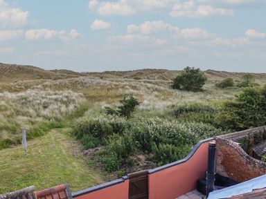 A garden with shrubs and grass beyond a red brick wall at Beach House in Winterton-On-Sea