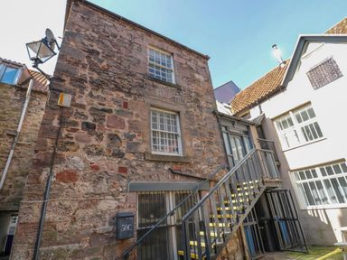 An exterior view of a stone building with metal stairs leading to a second-floor door at The Old Factory House in Berwick-Upon-Tweed