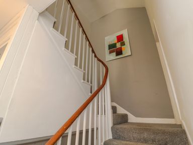 A staircase with grey carpet and a wooden handrail with white balusters at The Old Factory House in Berwick-Upon-Tweed