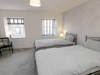 A bedroom with two metal frame beds a chair a lamp and two windows at The Old Factory House in Berwick-Upon-Tweed