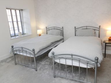 A bedroom with two single metal frame beds and one bedside table with a lamp at The Old Factory House in Berwick-Upon-Tweed