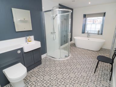 A bathroom with a toilet sink shower and bathtub and patterned floor at The Old Factory House in Berwick-Upon-Tweed